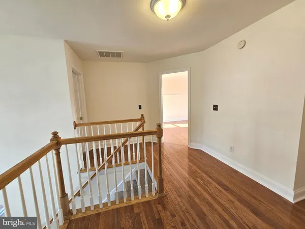 a view of a hallway with wooden floor and stairs