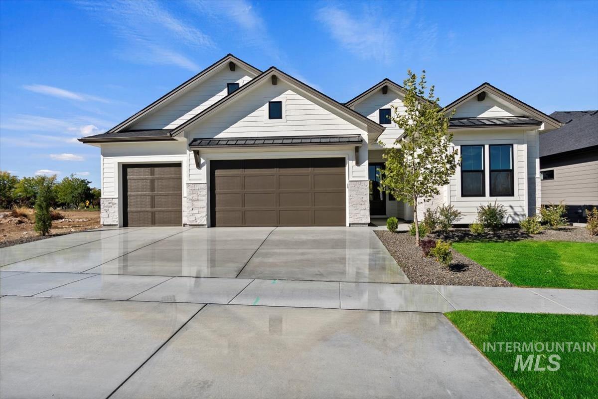 7353 Powell Place Eagle, ID 83714 - Photo 1 of 46 View of front of house featuring a standing seam roof, a metal roof, driveway, stone siding, and a garage