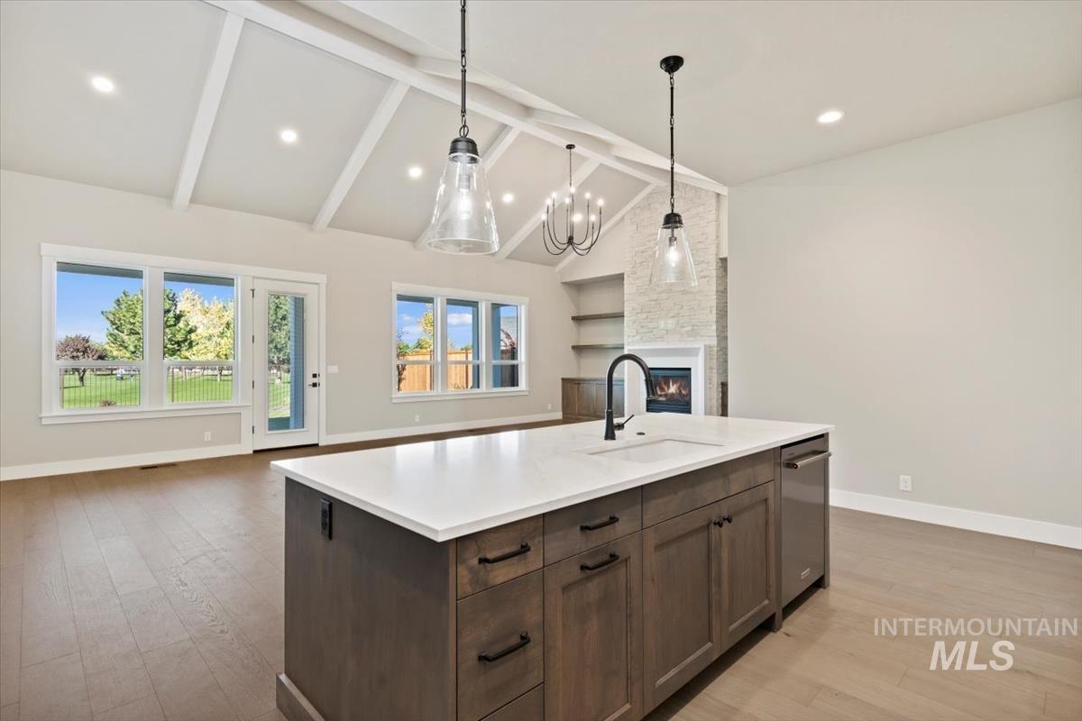 7353 Powell Place Eagle, ID 83714 - Photo 45 of 45 Kitchen featuring a fireplace, open floor plan, decorative light fixtures, a kitchen island with sink, and high vaulted ceiling