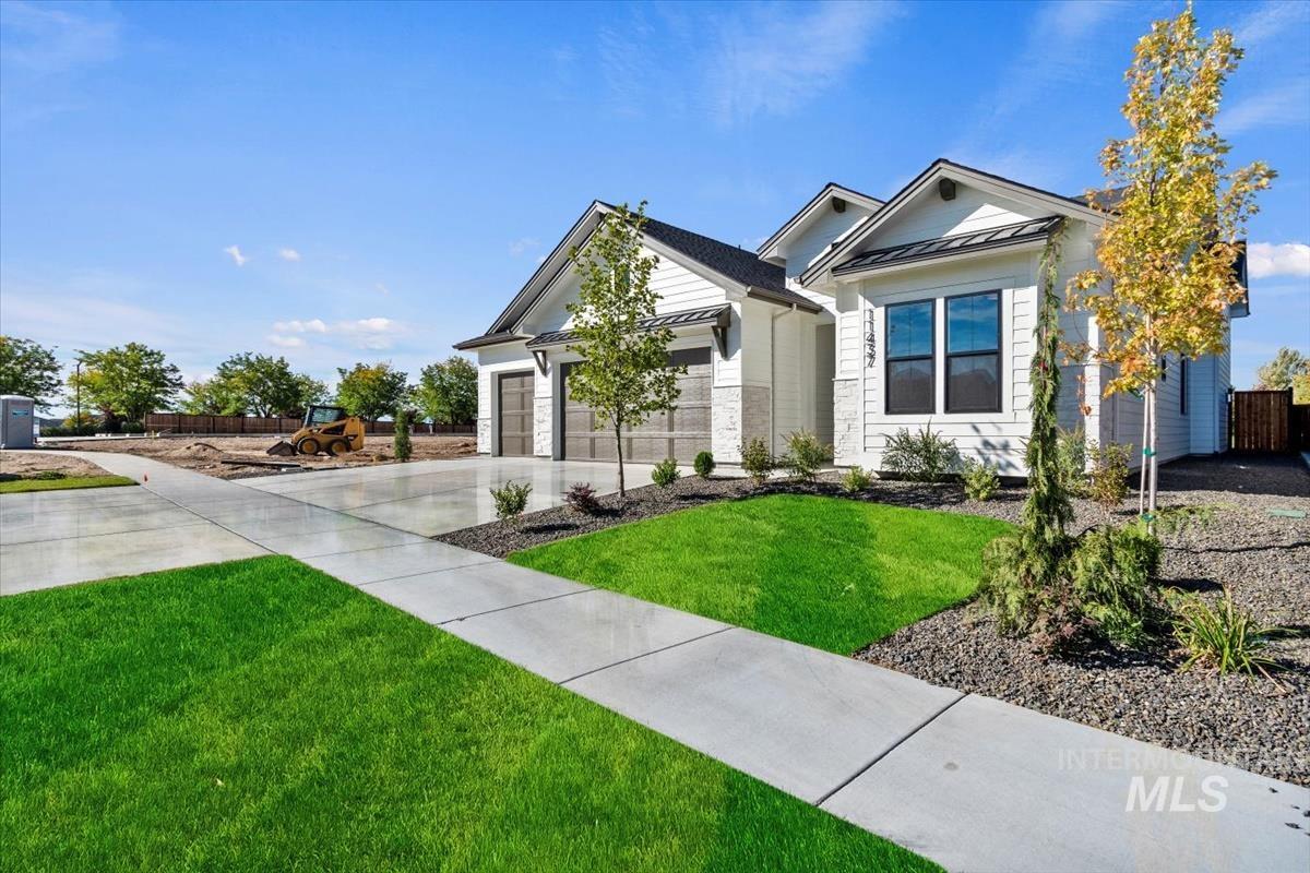 7353 Powell Place Eagle, ID 83714 - Photo 2 of 46 View of front of house featuring a standing seam roof, a metal roof, concrete driveway, a garage, and stone siding