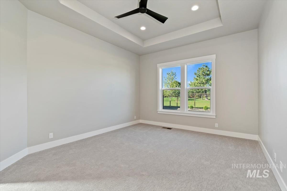 7353 Powell Place Eagle, ID 83714 - Photo 22 of 45 Empty room featuring a ceiling fan, light colored carpet, recessed lighting, and a raised ceiling