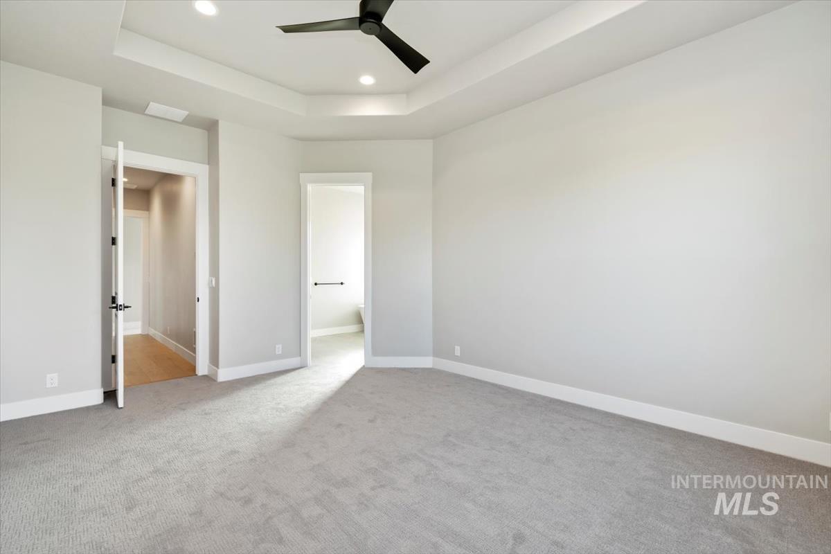 7353 Powell Place Eagle, ID 83714 - Photo 24 of 45 Unfurnished bedroom with a raised ceiling, light colored carpet, a ceiling fan, and recessed lighting