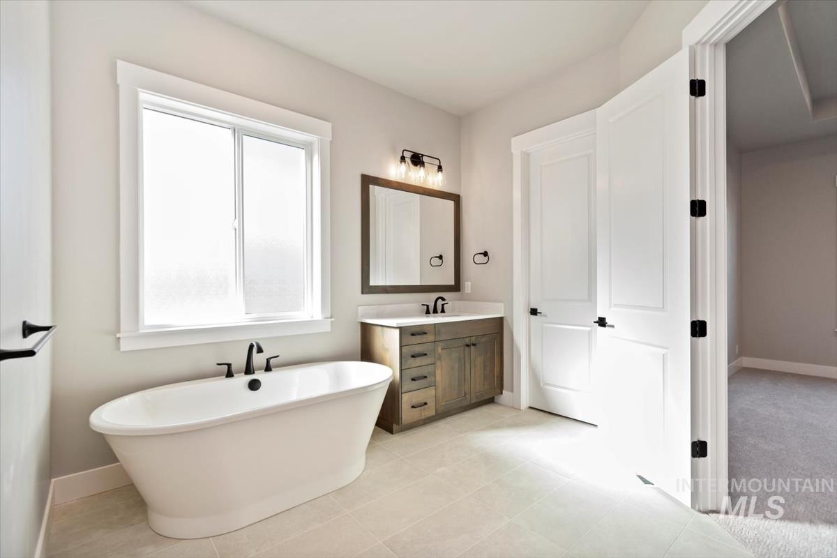 7353 Powell Place Eagle, ID 83714 - Photo 25 of 45 Full bathroom with a freestanding bath, vanity, and light tile patterned flooring