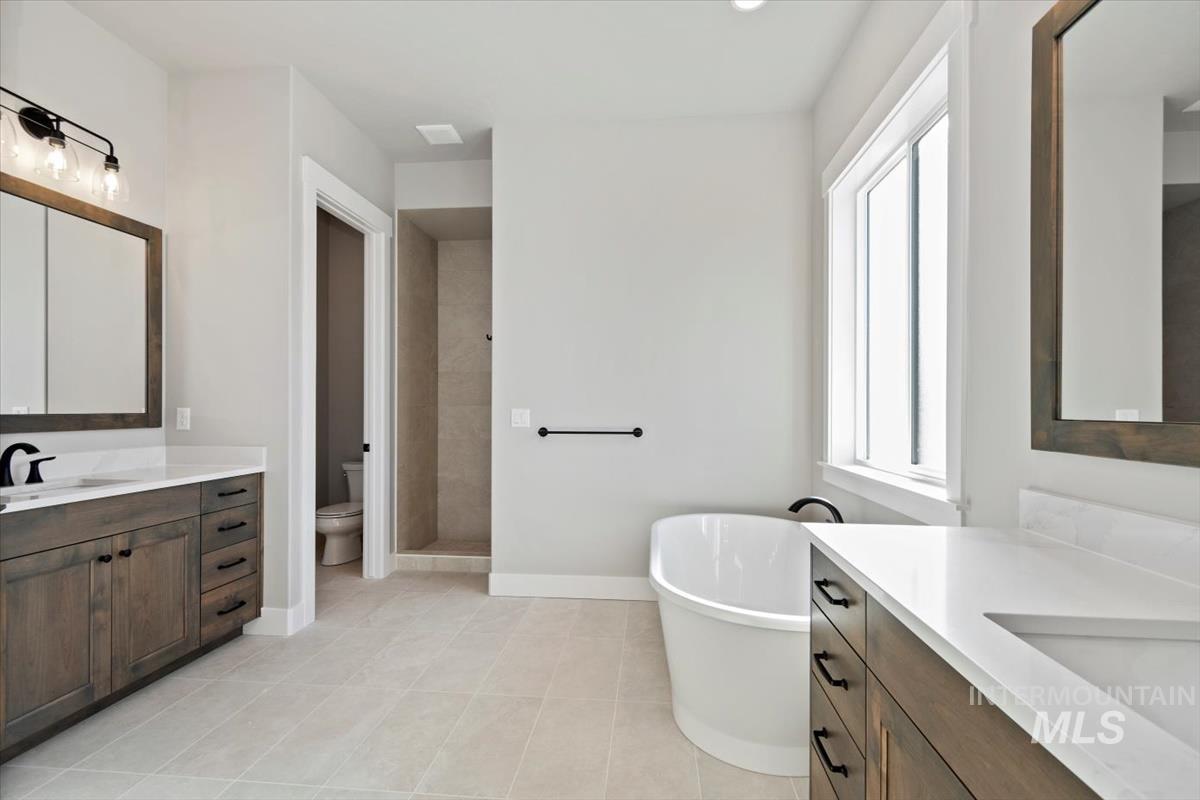 7353 Powell Place Eagle, ID 83714 - Photo 27 of 46 Full bath with two vanities, a soaking tub, tiled shower, and light tile patterned floors