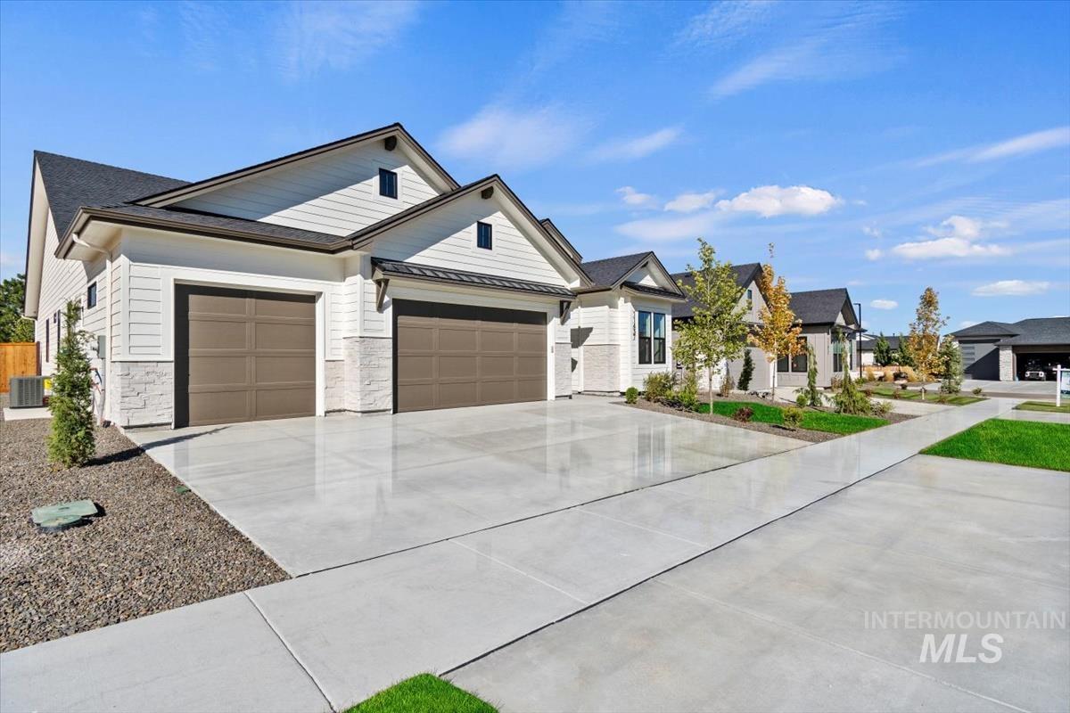 7353 Powell Place Eagle, ID 83714 - Photo 3 of 46 Modern farmhouse featuring driveway, an attached garage, stone siding, a standing seam roof, and a metal roof