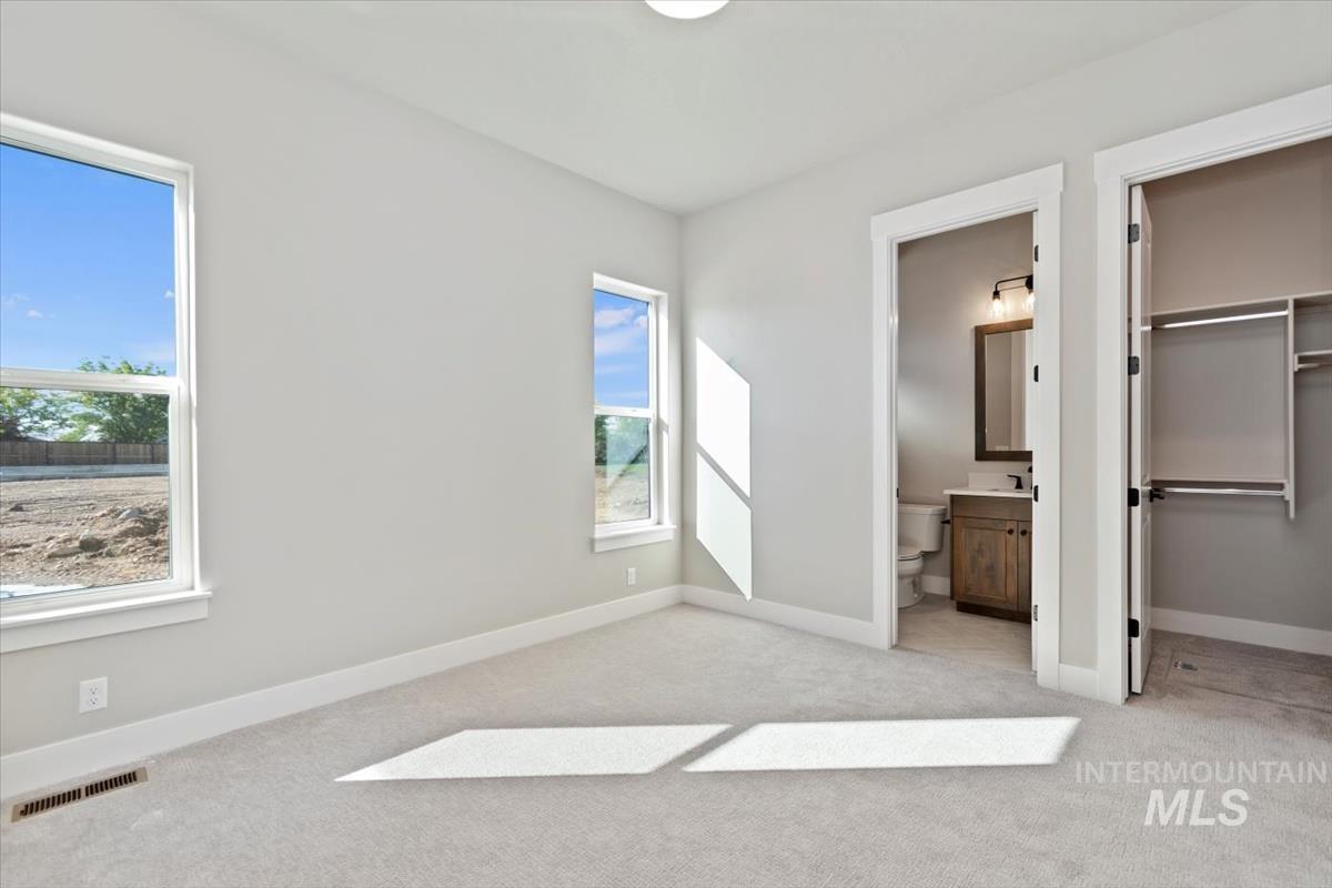 7353 Powell Place Eagle, ID 83714 - Photo 31 of 45 Unfurnished bedroom with light carpet, a spacious closet, and connected bathroom