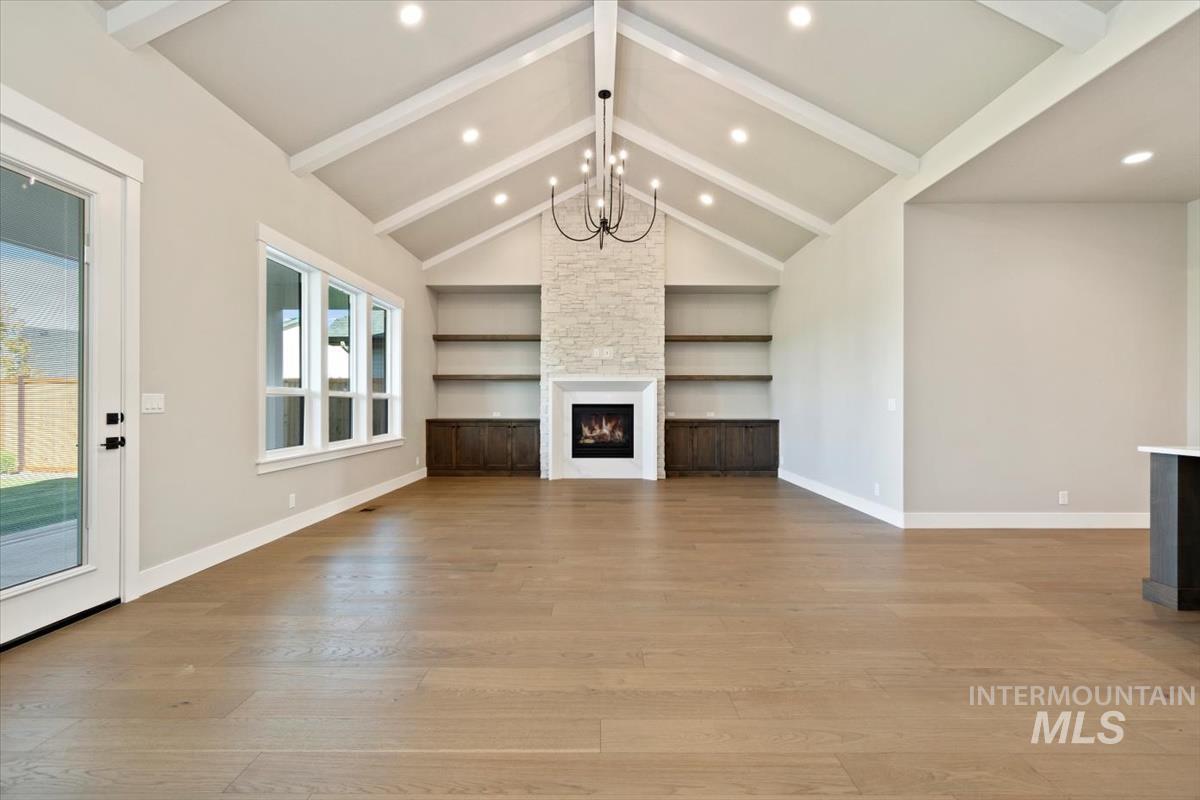 7353 Powell Place Eagle, ID 83714 - Photo 7 of 45 Unfurnished living room featuring a fireplace, a chandelier, built in features, light wood-style floors, and recessed lighting