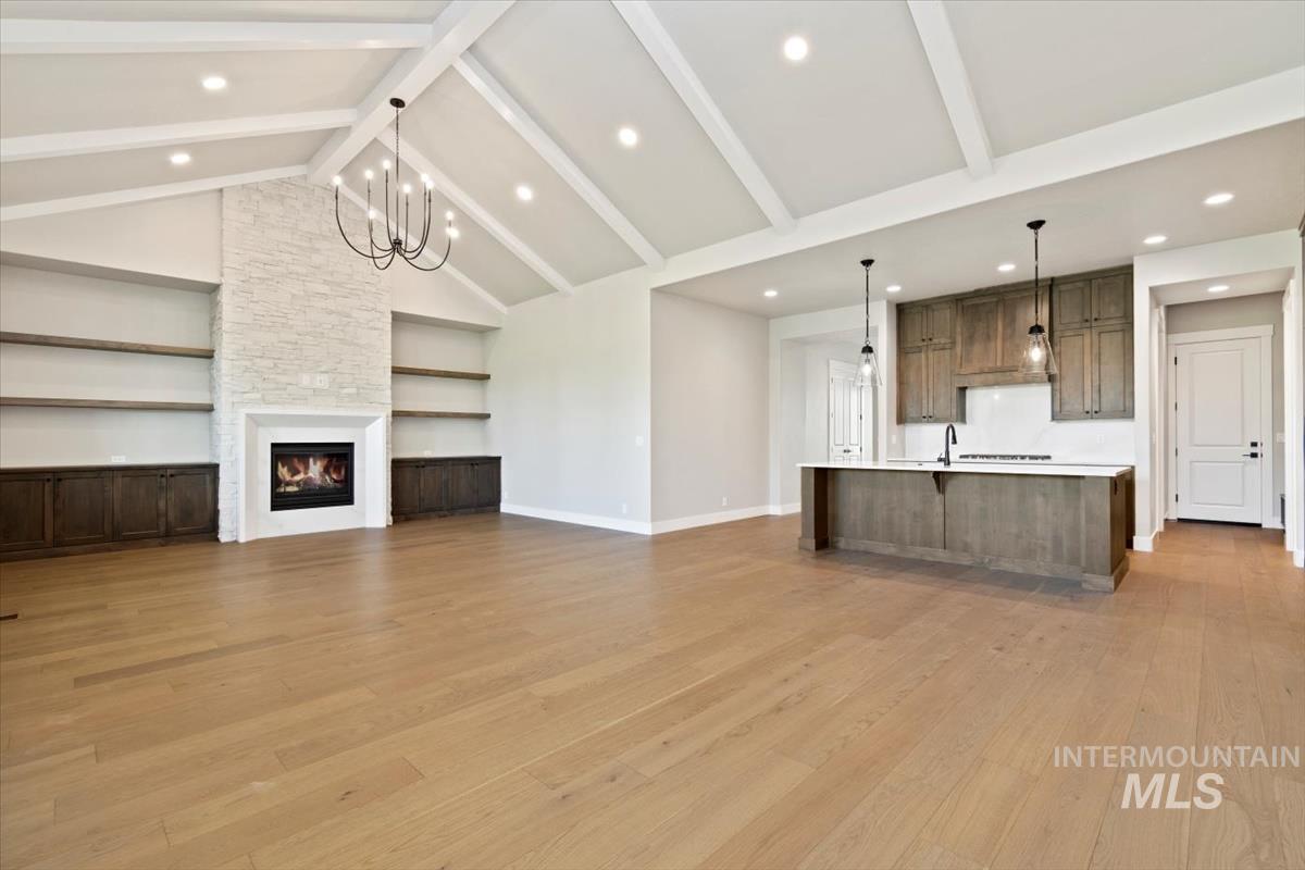 7353 Powell Place Eagle, ID 83714 - Photo 8 of 45 Unfurnished living room with built in features, a stone fireplace, light wood finished floors, beam ceiling, and high vaulted ceiling