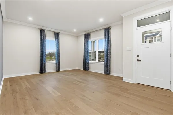 a view of an empty room with wooden floor and a window