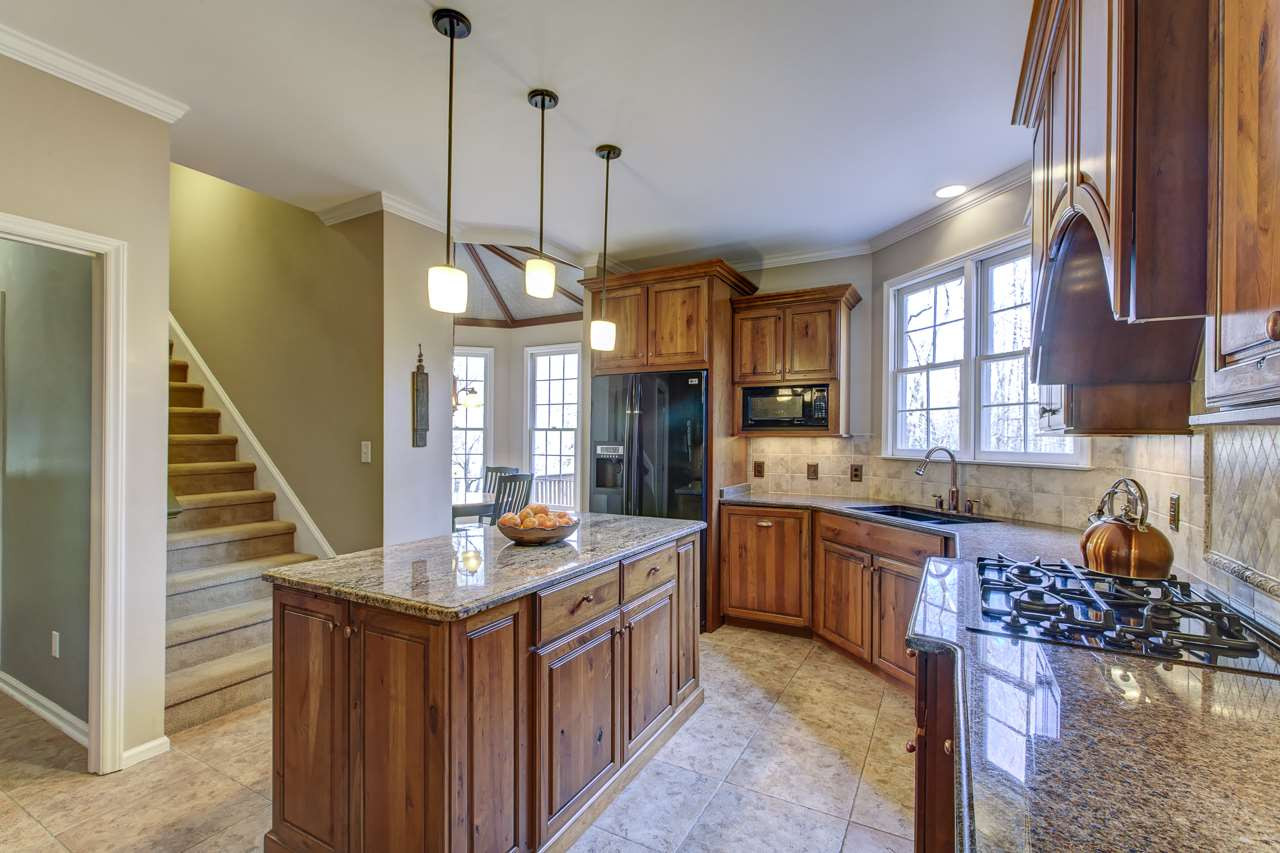 12312 Galway Drive Raleigh, NC 27613 - Photo 7 of 25 Cooking is a breeze in the gourmet kitchen that offers 42” knotty cherry cabinets with crown, granite counters, a center island with three pendant lights, a glass display cabinet, walk-in pantry, gas cooktop, double Bosch ovens, and an LG refrigerator. Kitchen