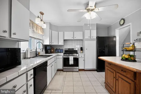 a kitchen with stainless steel appliances granite countertop a sink a stove a refrigerator cabinets and entryway