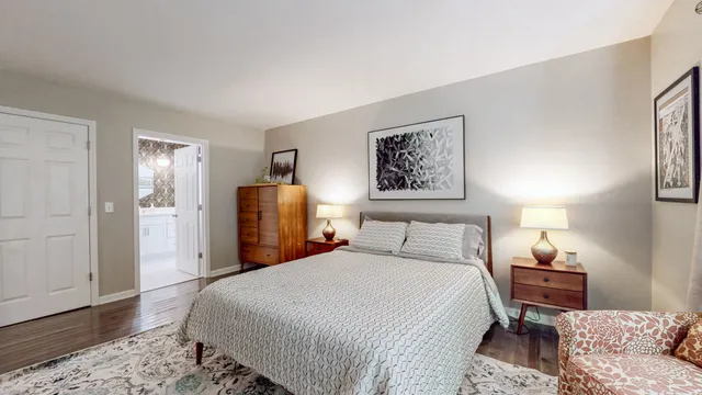a bedroom with a bed a dresser and wooden floor
