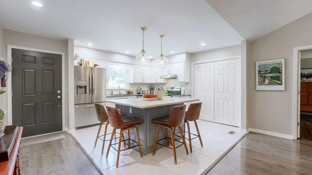 a kitchen with stainless steel appliances kitchen island granite countertop a refrigerator a sink a dining table and chairs