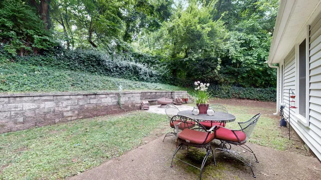 a backyard with table and chairs and potted plants
