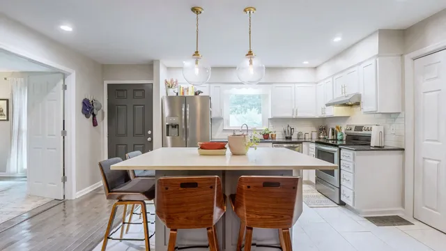 a kitchen with stainless steel appliances kitchen island granite countertop a table chairs stove and refrigerator