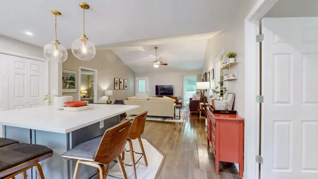 a view of a dining room and livingroom with furniture wooden floor a chandelier