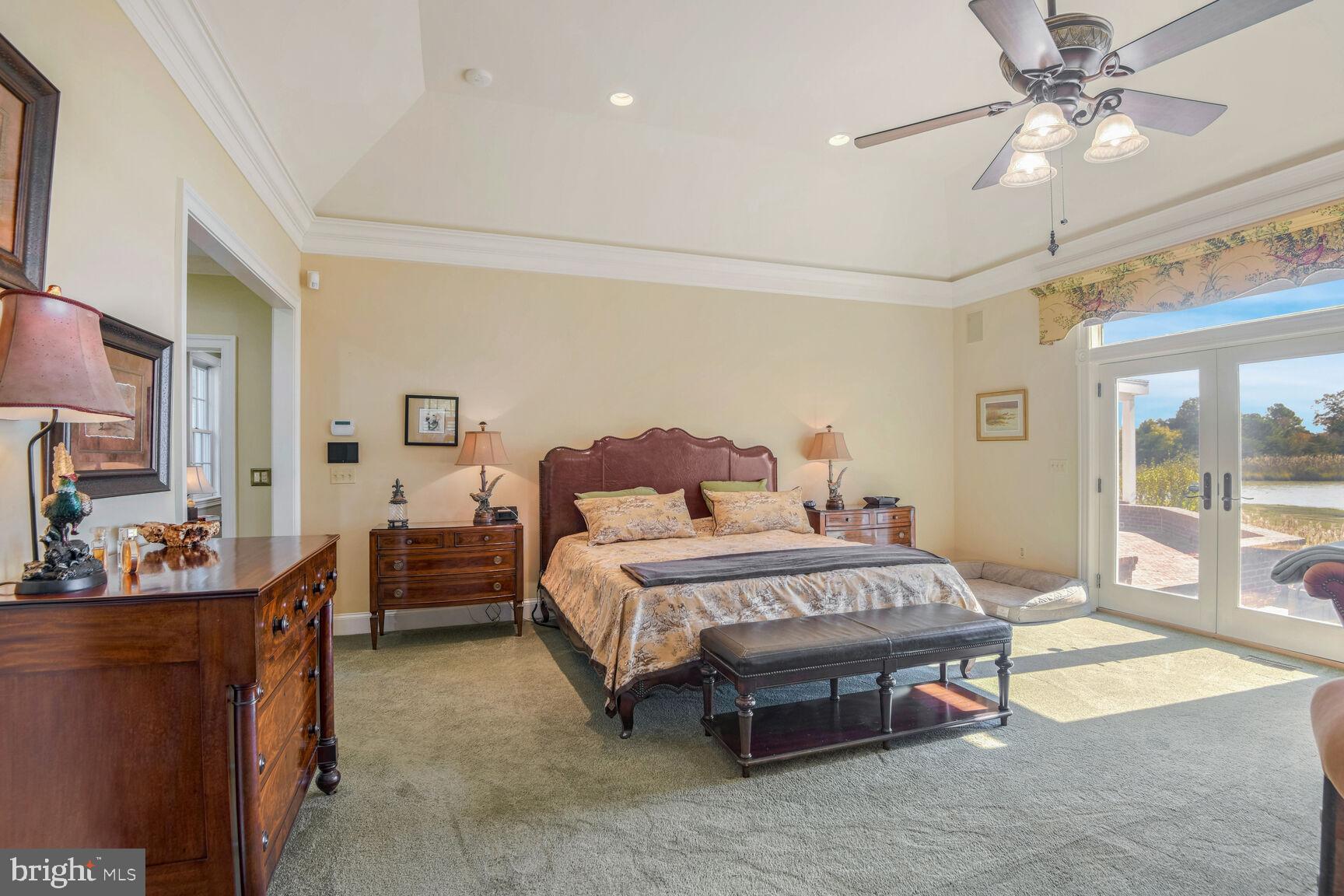 5289 Ferry Neck Road Royal Oak, MD 21662 - Photo 32 of 80 a spacious bedroom with a bed a chandelier and mirror