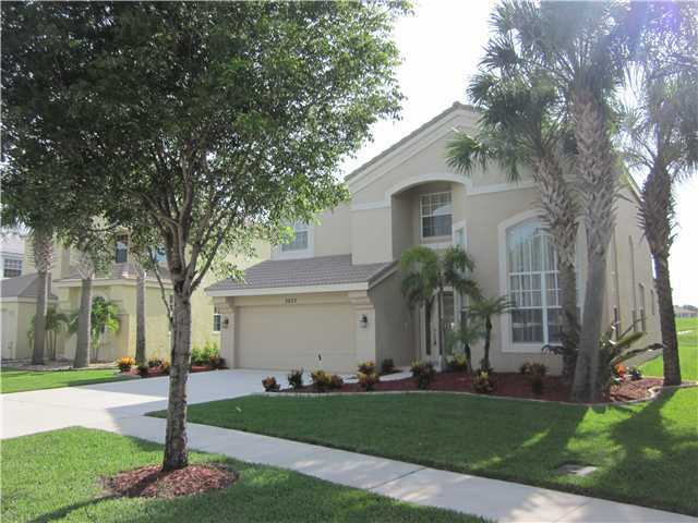 a front view of a house with a garden and trees