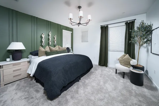 a bedroom with a bed a chandelier and a large mirror