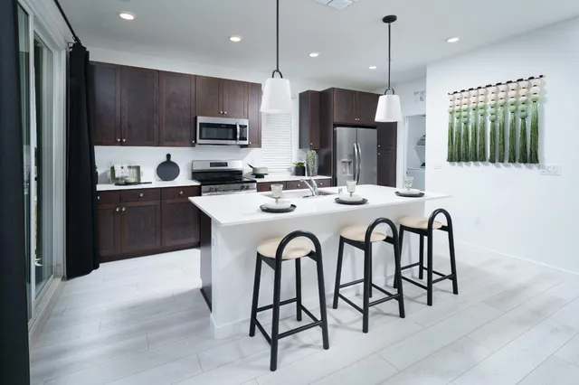 a kitchen with stainless steel appliances kitchen island granite countertop a dining table and chairs