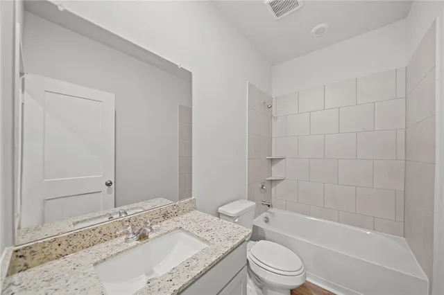 a bathroom with a granite countertop sink a toilet and bathtub