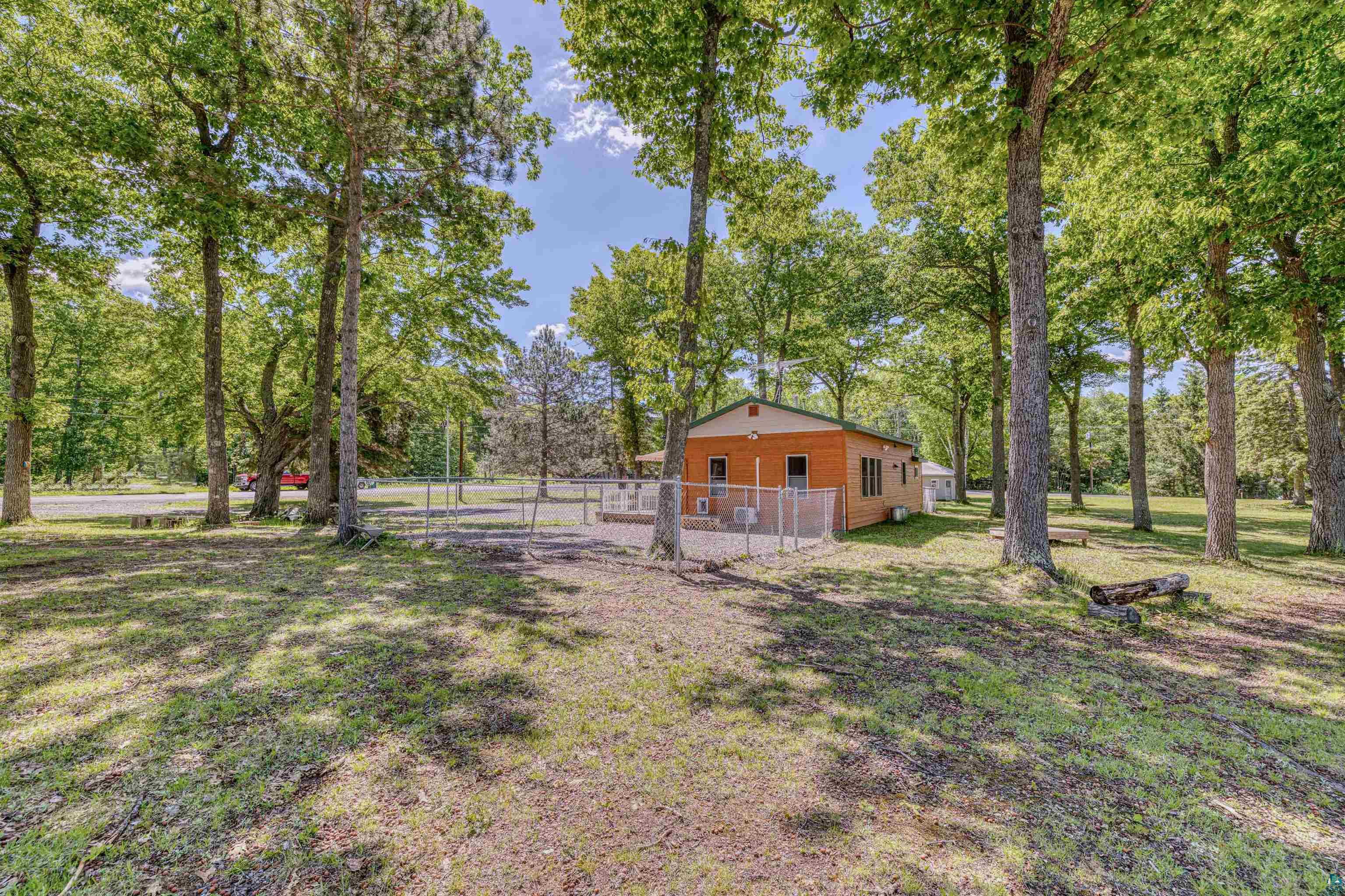 66075 Rooster Road Iron River, WI 54847 - Photo 46 of 52 Wood-sided structure with a green-trimmed roof, surrounded by mature trees, featuring a chain-link fence enclosure