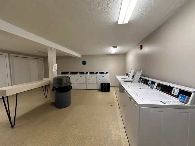 a living room with stainless steel appliances kitchen island a sink a stove and white cabinets