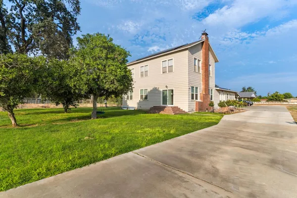 a view of a house with backyard and trees