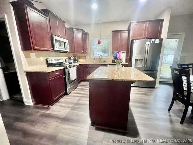 a kitchen with stainless steel appliances a dining table chairs refrigerator and sink