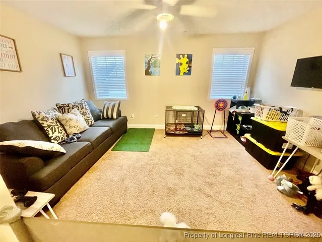 a living room with furniture a flat screen tv and a window