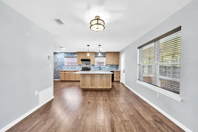 a large kitchen with a center island wooden floor and stainless steel appliances