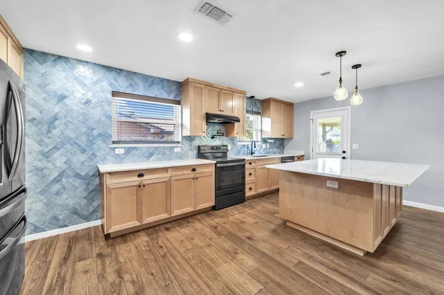 a large kitchen with stainless steel appliances granite countertop a stove a sink dishwasher and a oven with wooden floors