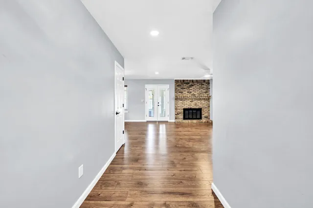 a view of a hallway with wooden floor and a window