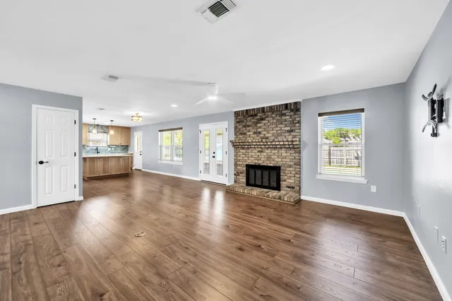 an empty room with wooden floor fireplace and windows