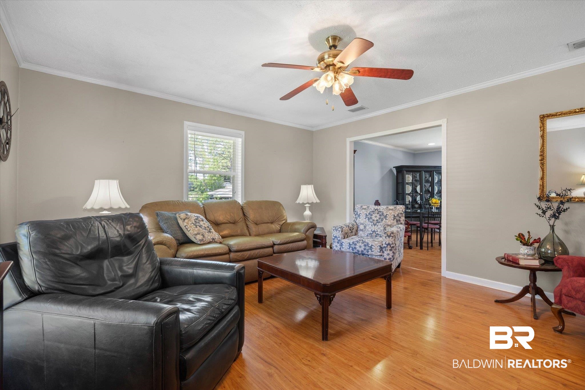 706 Sutherland Drive Chickasaw, AL 36611 - Photo 11 of 33 Living room with light wood-type flooring, baseboards, visible vents, ceiling fan, and ornamental molding