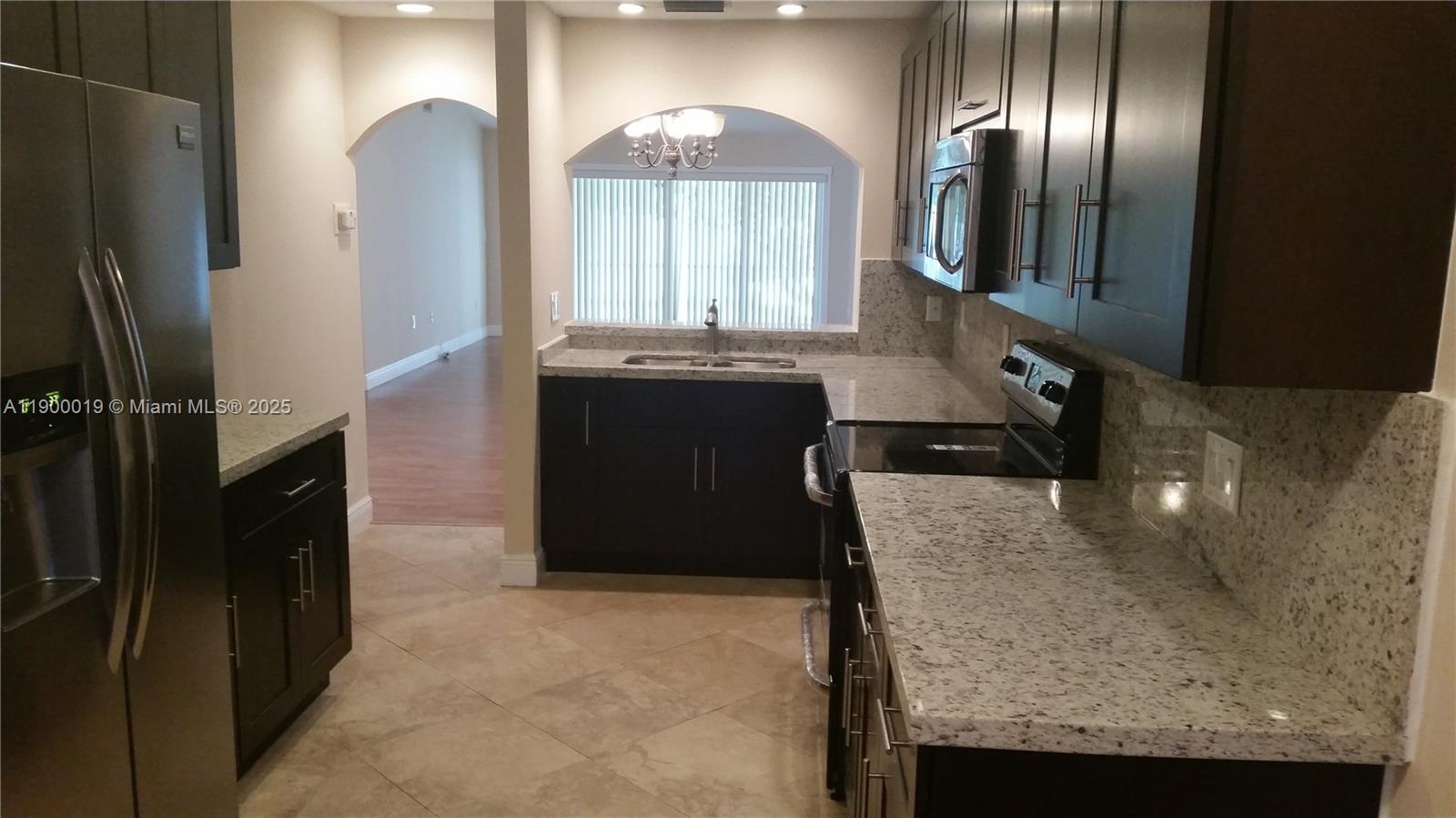 11071 Southwest 11th Place, Unit 124 Davie, FL 33324 - Photo 3 of 18 a kitchen with granite countertop stainless steel appliances a refrigerator and stove