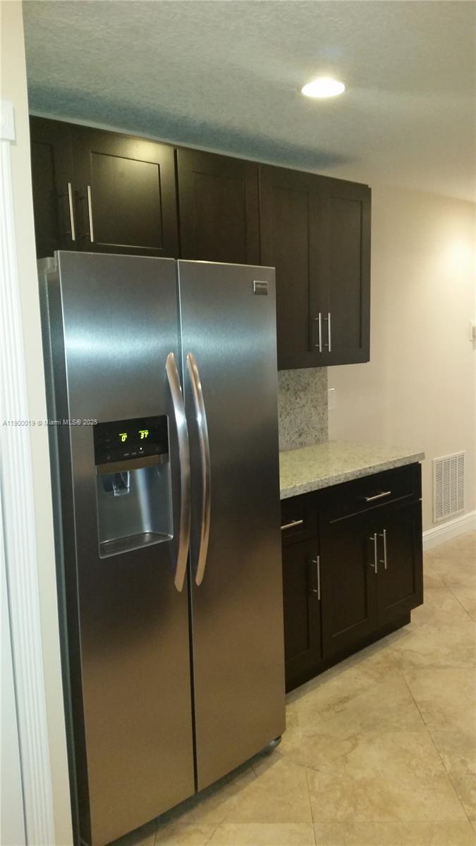 11071 Southwest 11th Place, Unit 124 Davie, FL 33324 - Photo 6 of 18 a kitchen with a refrigerator and cabinets