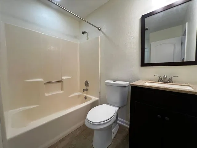 a bathroom with a toilet a sink a mirror a bathtub and vanity