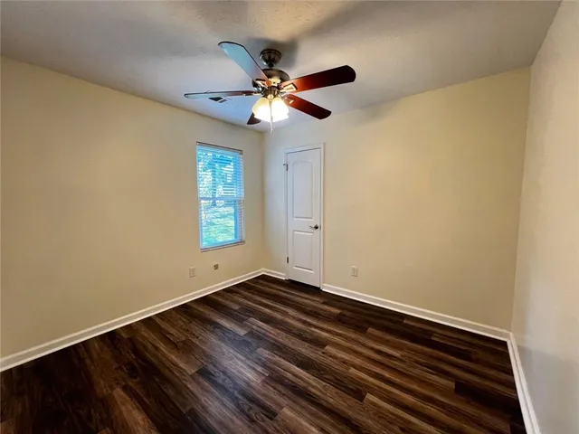 a view of an empty room with window and wooden floor