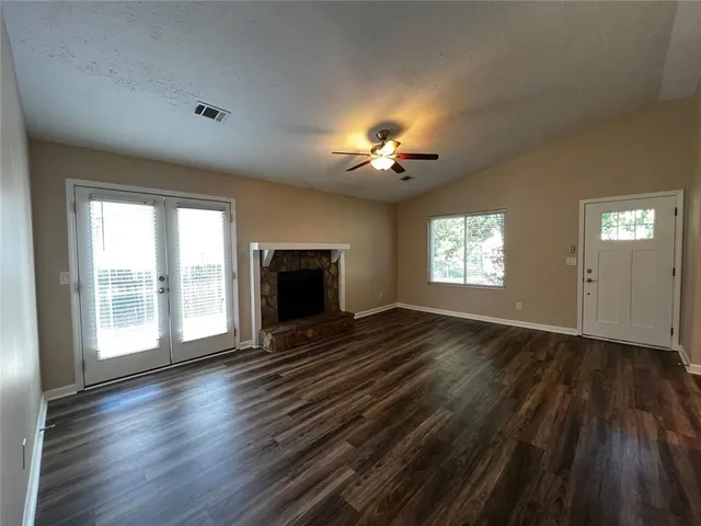 an empty room with windows a fireplace and wooden floor