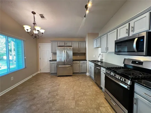 a kitchen with granite countertop a stove cabinets and refrigerator
