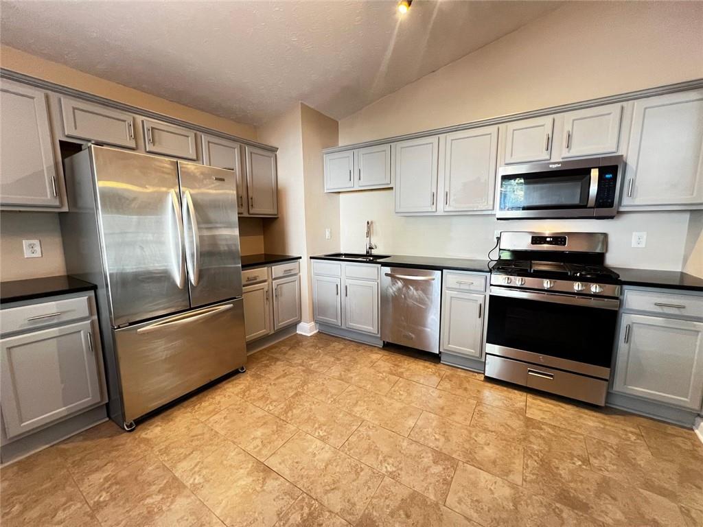4170 Shiloh Ridge Trail Kennesaw, GA 30144 - Photo 6 of 19 a kitchen with stainless steel appliances granite countertop a stove a sink and a refrigerator