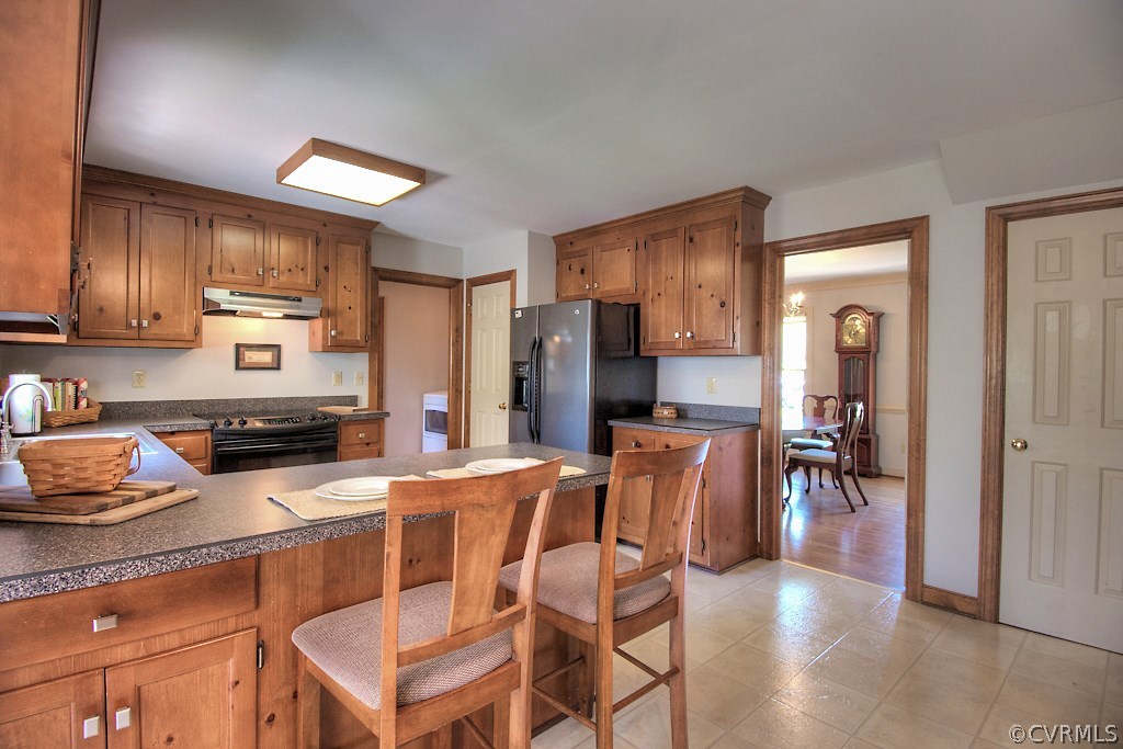 4602 Twin Cedars Road Chester, VA 23831 - Photo 14 of 47 a kitchen with stainless steel appliances granite countertop a refrigerator a stove a sink a dining table and chairs with wooden floor