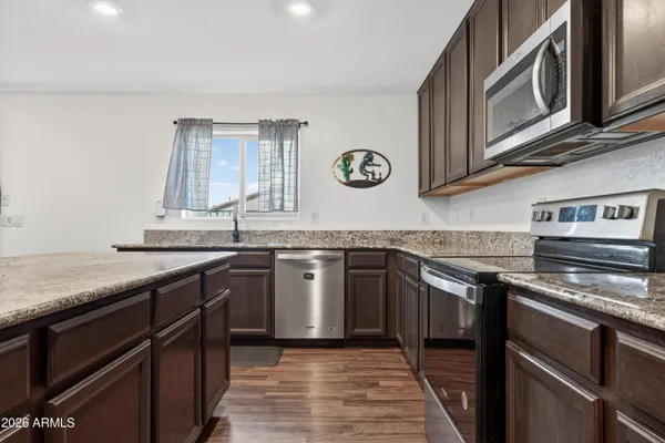 a kitchen with stainless steel appliances granite countertop a sink a stove a refrigerator cabinets and chairs