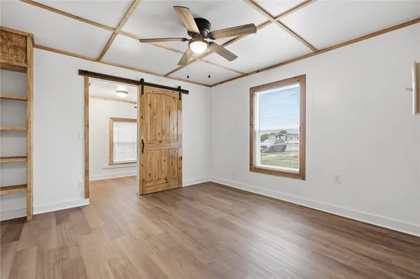 a view of an empty room with a window and wooden floor