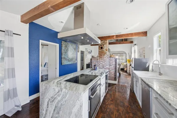a kitchen with stainless steel appliances kitchen island granite countertop a sink a stove and refrigerator