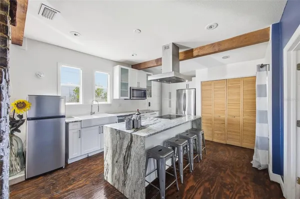 a kitchen with stainless steel appliances kitchen island granite countertop a table chairs in it and wooden floors