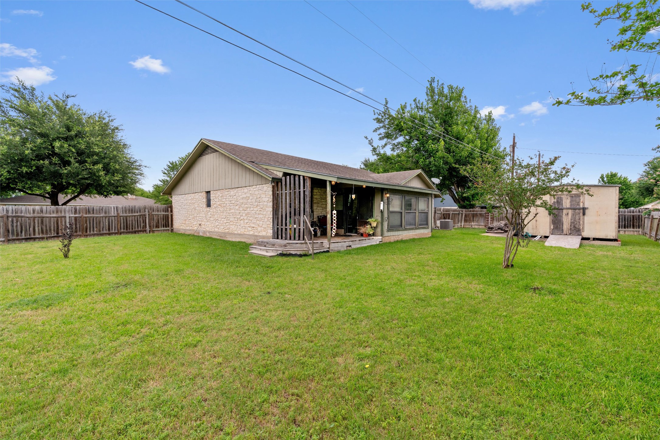 401 Drake Lane Taylor, TX 76574 - Photo 28 of 31 Expansive backyard featuring a manicured lawn, full privacy fencing, and a built-in storage shed