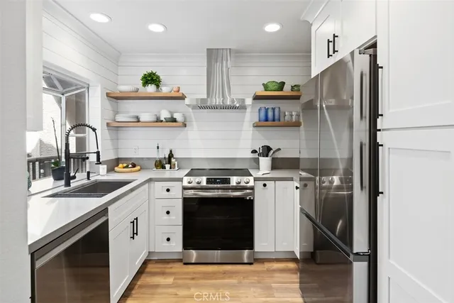 a kitchen with stainless steel appliances granite countertop a refrigerator a sink a stove and white cabinets