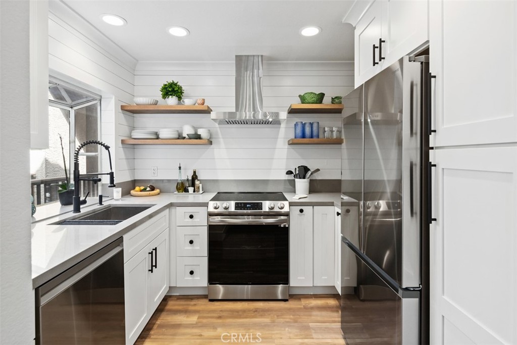 a kitchen with stainless steel appliances granite countertop a refrigerator a sink a stove and white cabinets